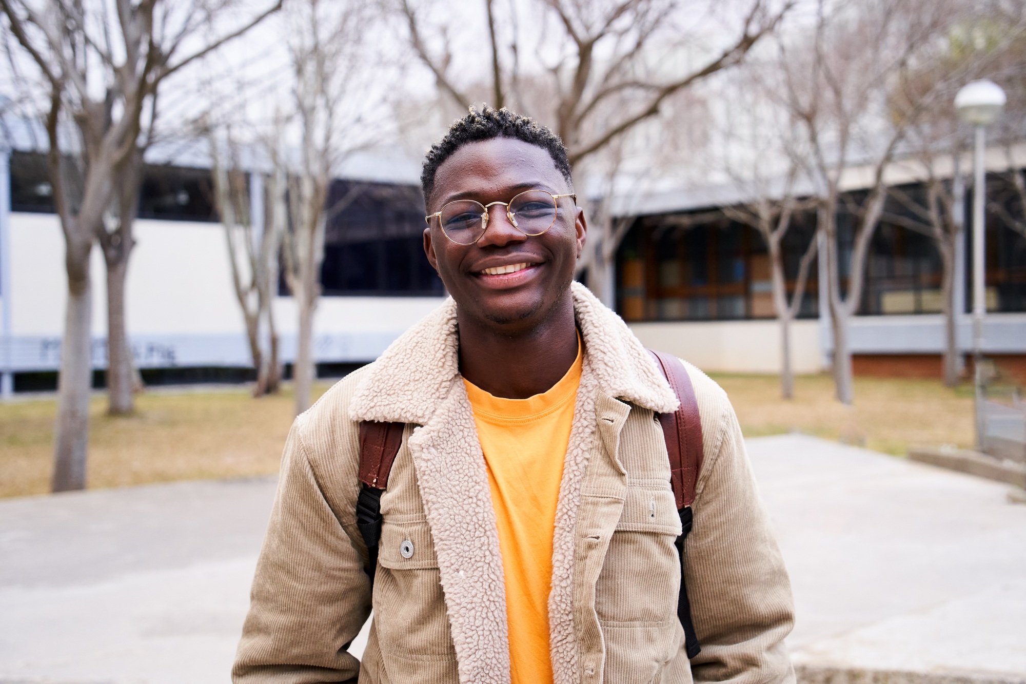 Close up shot of cheerful happy African American teen looking at camera smiling. Young student man